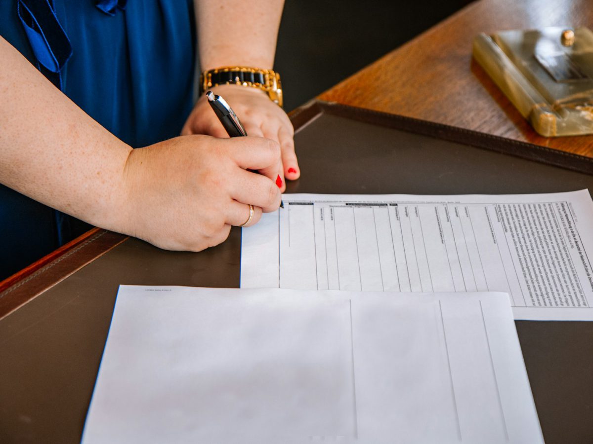 person holding pen and writing on paper